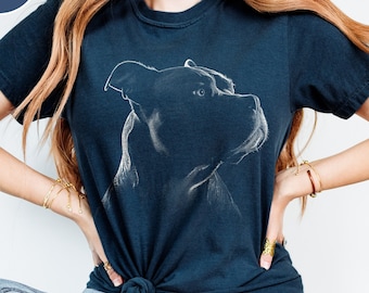 May include: A true navy blue short-sleeve t-shirt featuring a white line-art illustration of a dog's head in profile on the chest. The shirt has a crew neckline and is tied in a knot at the front waist, paired with light blue denim jeans.