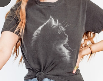 May include: A charcoal gray short-sleeve t-shirt featuring a white graphic print of a cat in profile on the chest. The shirt has a crew neckline and is tied in a knot at the front hem. The word PEPPER is printed in white inside a dark circle.