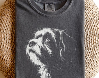 May include: A charcoal gray crew neck t-shirt featuring a white line art illustration of a dog's head in profile. The shirt has a visible brand label at the inner neckline and is made of a soft, garment-dyed fabric with a slightly faded appearance.