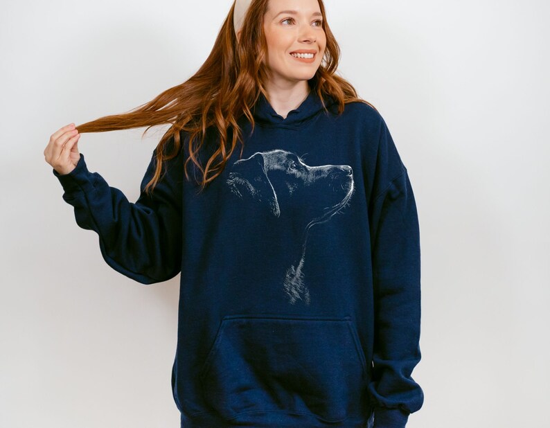 May include: A navy blue hooded sweatshirt featuring a white line art illustration of a dog's profile on the chest. The garment includes a front kangaroo pocket, long sleeves with ribbed cuffs, and a drawstring hood, providing a casual look.