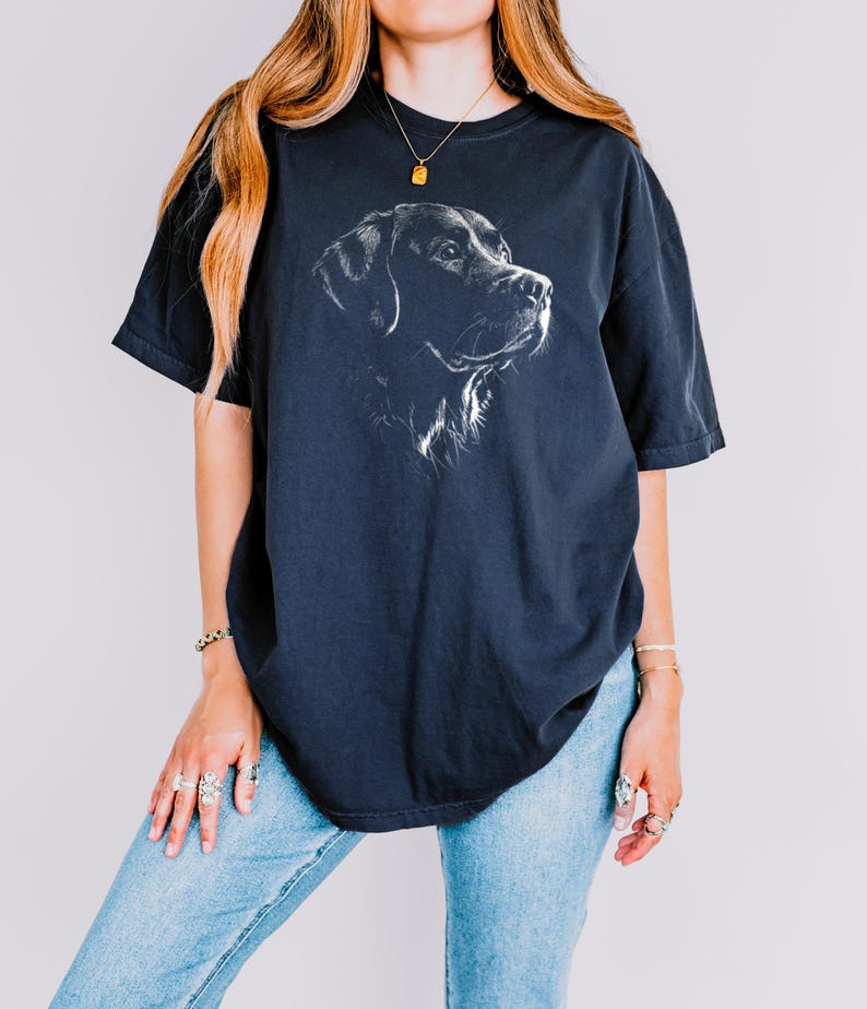 Op de afbeelding: Een donker antracietgrijs T-shirt met korte mouwen en een witte lijntekening van de kop van een Labrador retriever in profiel op de borst. Het T-shirt heeft een ronde hals en een ruimvallend, los model.
