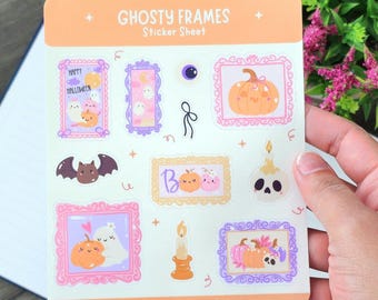 May include: A sticker sheet with the text "GHOSTY FRAMES" and various Halloween-themed illustrations. The stickers feature ghosts, pumpkins, bats, and candles in frames. The colour palette includes orange, pink, purple, and white.
