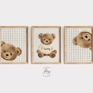 May include: A set of three framed prints with watercolour illustrations of teddy bears. One bear is centered, wearing a sweater with "Teddy" on it. The other two prints show the bear's face peeking from the side. The background is a light beige and white checkered pattern.