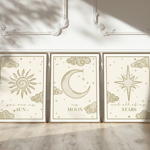 May include: Three framed art prints with celestial designs. Each print features a different celestial body: a sun, a crescent moon, and a star. The prints are in a neutral color palette with gold frames and include the phrases "you are my SUN", "my MOON", and "and all of my STARS".