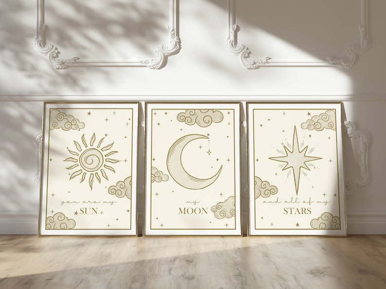 May include: Three framed art prints with celestial designs. Each print features a different celestial body: a sun, a crescent moon, and a star. The prints are in a neutral color palette with gold frames and include the phrases "you are my SUN", "my MOON", and "and all of my STARS".
