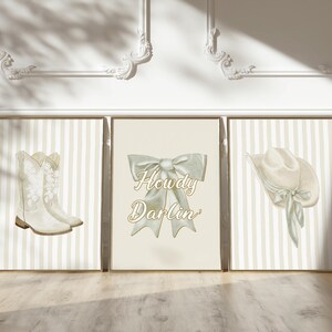 May include: Three framed prints with a country theme. The left print shows white cowboy boots, the center print has a bow with the text "Howdy Darlin'", and the right print features a cowboy hat. All prints have a striped background.