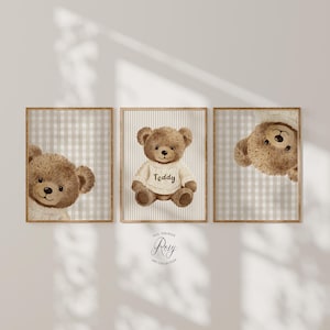 May include: Three framed prints with watercolour illustrations of teddy bears. One bear wears a sweater with the word "Teddy". The backgrounds feature neutral gingham and striped patterns. The artwork has a soft, muted colour palette.