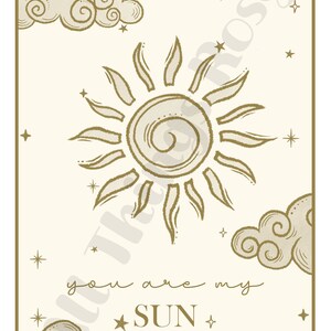 May include: A beige print featuring a sun design with radiating lines, clouds, and stars. The text "you are my SUN" is written in a script font. The artwork has a gold border and is suitable for wall decor.