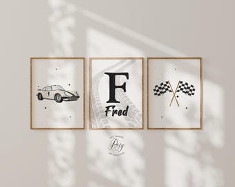 May include: Three framed prints with a racing theme. The prints feature a vintage car, the letter "F" with the name "Fred", and crossed checkered flags. The prints are in neutral tones with a minimalist design, perfect for a nursery or child's room.