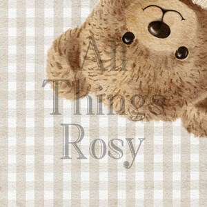 May include: A watercolour illustration of a teddy bear wearing a cream-coloured knitted hat. The bear is brown with black eyes and nose. The text "All Things Rosy" is printed in a light grey font over a beige and white checked background.