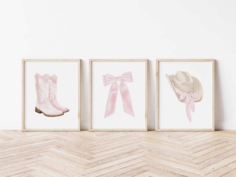 K&ouml;nnte beinhalten: Drei gerahmte Aquarelldrucke mit Western-Thema. Die Drucke zeigen ein Paar rosa Cowboystiefel, eine rosa Schleife und einen Cowboyhut mit rosa Band. Das Kunstwerk ist vor einem wei&szlig;en Hintergrund.