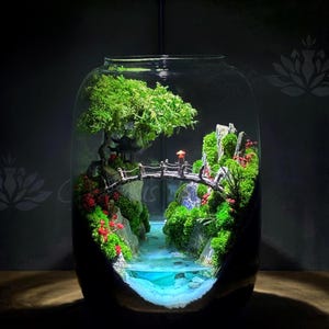 Pode incluir: Uma cena de jardim japonês em miniatura dentro de um frasco de vidro. A cena inclui uma pequena ponte, um riacho e vegetação exuberante. O frasco é iluminado por uma pequena luz, criando uma atmosfera tranquila e serena.
