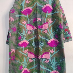 May include: A long, gray embroidered coat featuring a floral design. The coat has a pattern of large, magenta and pink flowers with teal stems and green leaves. The sleeves are three-quarter length. The coat is made of a soft, textured fabric.