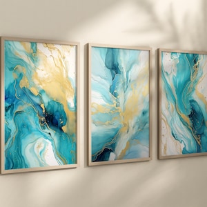 Könnte beinhalten: Drei gerahmte abstrakte Kunstdrucke mit einem blauen und goldenen Marmormuster. Die Drucke sind in einem hellen Holzrahmen und hängen an einer weißen Wand.
