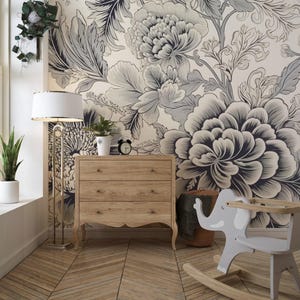Peut inclure: Un papier peint floral blanc et gris avec une grande fleur noire et blanche au premier plan. Une commode en bois à trois tiroirs se trouve au milieu de l'image. Un cheval à bascule en forme d'éléphant se trouve dans le coin inférieur droit de l'image.