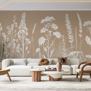 Peut inclure: Un intérieur de salon avec un mur beige orné d'un papier peint floral blanc. La pièce est équipée d'un canapé blanc, de deux chaises en bois et de deux tables basses.