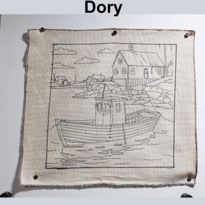 May include: A beige fabric wall hanging featuring a black line drawing of a boat, buildings, and water. The word "Dory" is at the top. The artwork has a dark border and is secured with four tacks.