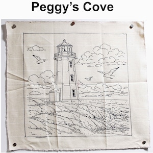 May include: A beige fabric square featuring a black line drawing of Peggy's Cove lighthouse, seagulls, and clouds. The text "Peggy's Cove" is at the top. The fabric is held in place with four tacks.