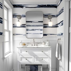 May include: White bathroom vanity with a white countertop and a rectangular mirror above the sink. The walls are covered in blue and white striped wallpaper.