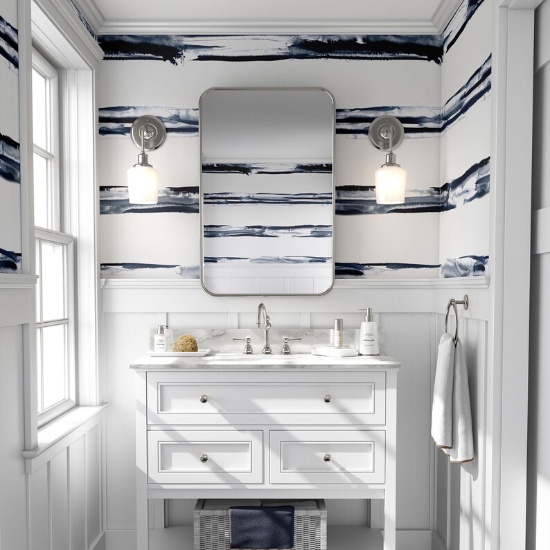 May include: White bathroom vanity with a white countertop and a rectangular mirror above the sink. The walls are covered in blue and white striped wallpaper.