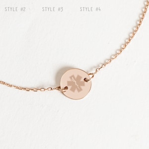Op de afbeelding: Roze gouden kettingarmband met een ronde bedel met een medisch symbool. De bedel heeft een ster-van-leven-ontwerp. De armband heeft een karabijn sluiting.