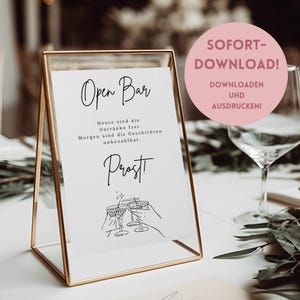 Può includere: Un cartello stampabile con il testo "Open Bar" in corsivo nero. Il cartello include anche il testo "Heute sind die Getränke frei. Morgen sind die Geschichten unbezahlbar. Prost!" in nero. Il cartello è incorniciato in una cornice dorata in metallo e si trova su un tavolo. Il cartello è un download stampabile.