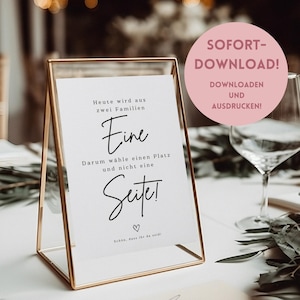 May include: A white sign with black text in a gold frame. The sign reads "Heute wird aus zwei Familien. Eine Darum wähle einen Platz und nicht eine Seite!" with a heart symbol and the text "Schön, dass ihr da seid!" at the bottom. The sign is on a table with a glass of water and greenery in the background. The text "SOFORT-DOWNLOAD! DOWNLOADEN UND AUSDRUCKEN!" is in a pink circle in the upper right corner of the image.
