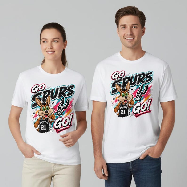 Op de afbeelding: Witte T-shirts met een kleurrijke afbeelding van een cartoon konijn met een basketbalshirt met nummer 21. De tekst "GO SPURS GO!" staat boven en onder het konijn. De shirts worden gedragen door een vrouw en een man.