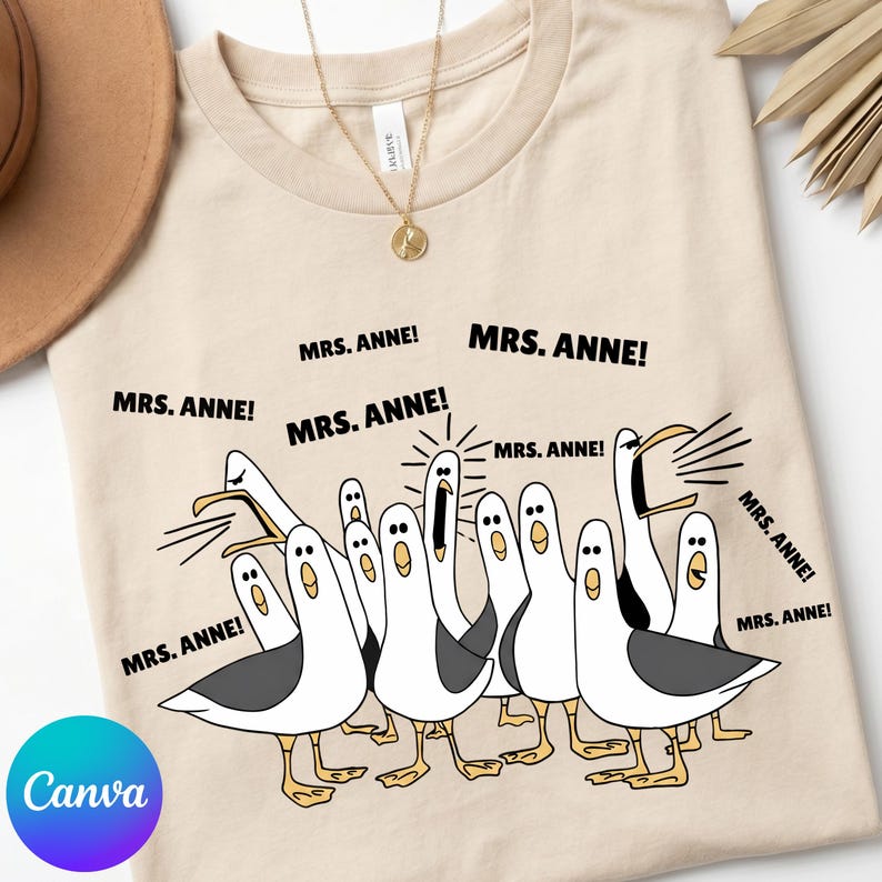 May include: Beige t-shirt featuring a cartoon illustration of seagulls with the text "MRS. ANNE!". The seagulls are white with gray wings and yellow feet. The shirt has a round neckline and short sleeves.