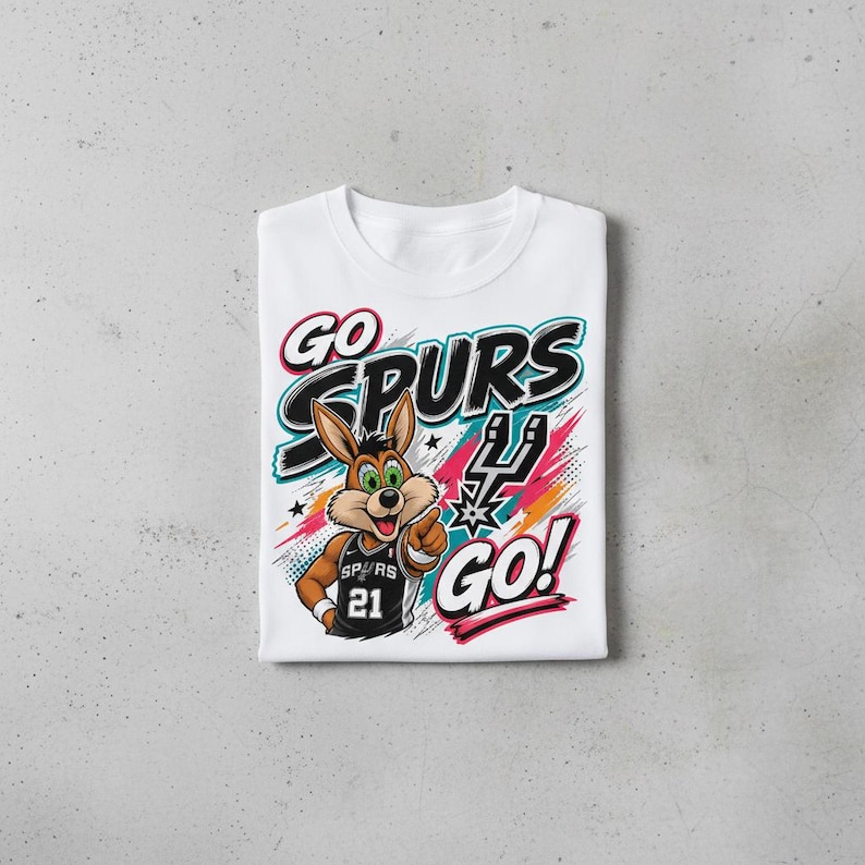 Op de afbeelding: Wit T-shirt met een cartoon konijn met een basketbalshirt met nummer 21. Het shirt toont de woorden "GO SPURS GO!" in een kleurrijk ontwerp, met het Spurs-logo prominent aanwezig.