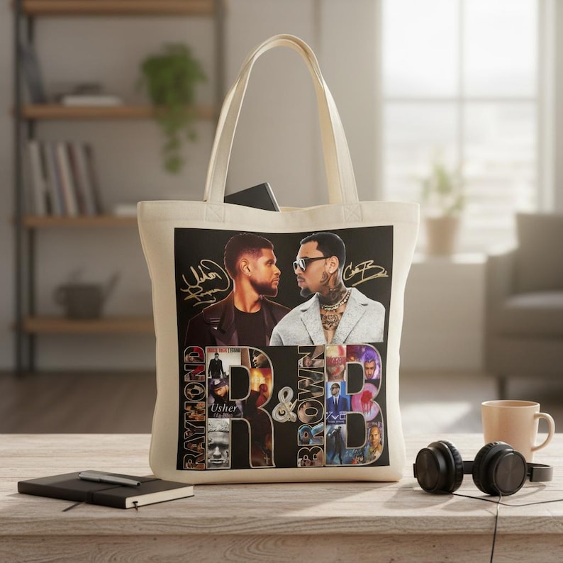 May include: Cream-colored tote bag featuring a graphic of two men with signatures, the words "Raymond" and "Brown", and the letters "R&B". The bag has a rectangular design and a handle.