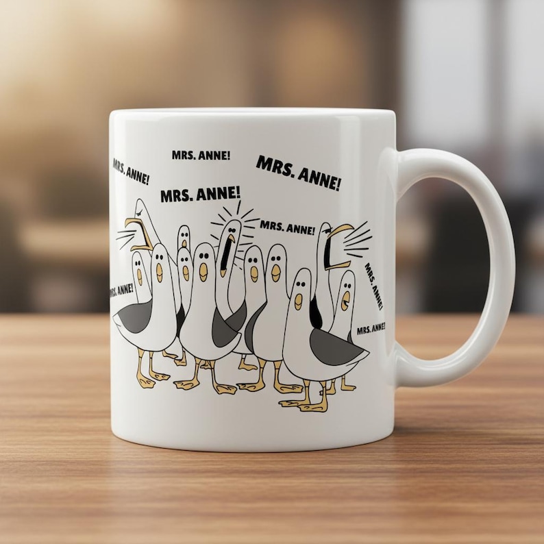 May include: White ceramic mug featuring a cartoon illustration of seagulls with the text "MRS. ANNE!" repeated around the image. The seagulls are depicted in black, white, and yellow, with various expressions. The mug has a curved handle.
