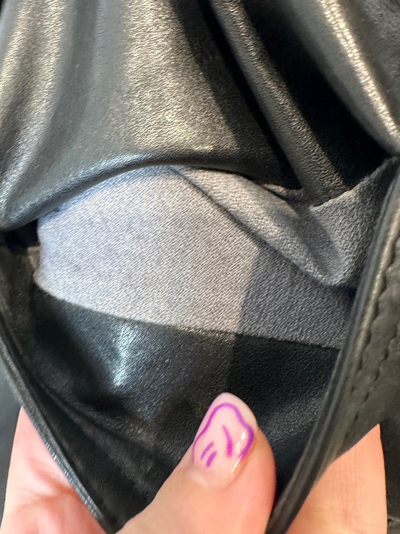 May include: Close-up of the inside of a black leather jacket, showing the gray lining. The lining is a soft, smooth fabric.