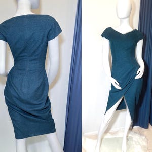 May include: A teal blue dress with a fitted bodice and a skirt that falls to the knee. The dress has a V-neckline and short sleeves.