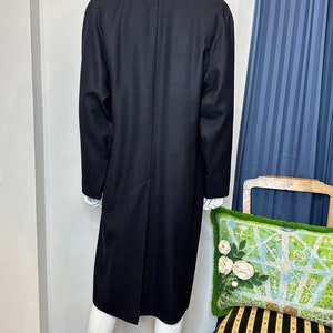 May include: A long, black wool coat with a single-breasted closure and a classic silhouette.