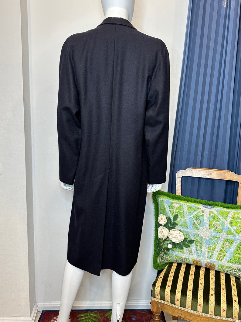 May include: A long, black wool coat with a single-breasted closure and a classic silhouette.