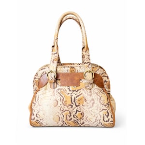 Könnte beinhalten: Handtasche mit Schlangenmuster, zwei Henkeln und strukturierter Form. Die Tasche hat eine Mischung aus Beige-, Braun- und Beigetönen mit Lederakzenten und goldfarbener Hardware. Die Tasche hat einen oberen Reißverschluss und eine rechteckige Form.