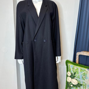 May include: A long black double-breasted coat with a classic collar and two pockets.