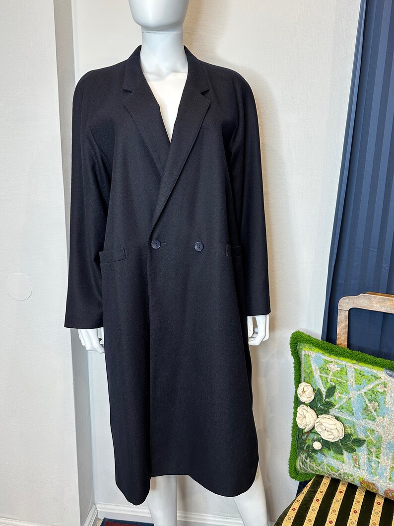 May include: A long black double-breasted coat with a classic collar and two pockets.