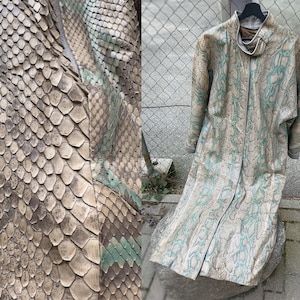 Könnte beinhalten: Ein langer Mantel mit Schlangenmuster in den Farben Beige, Braun und Türkis. Der Mantel hat einen hohen Kragen und ein bodenlanges Design. Das Schlangenmuster ist detailliert und bedeckt den gesamten Mantel.