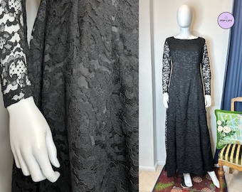 May include: A black lace maxi dress with long sleeves. The dress has a fitted bodice and a flowing skirt.