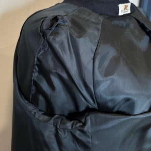 May include: Black jacket with a small tear on the shoulder. The jacket has a black satin lining.