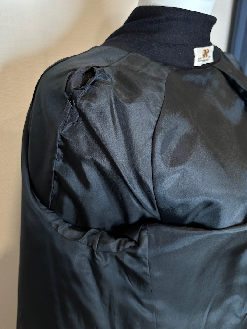 May include: Black jacket with a small tear on the shoulder. The jacket has a black satin lining.