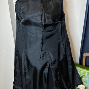 May include: Black long coat with a center back vent and a black satin lining. The coat has a JC Penney label.