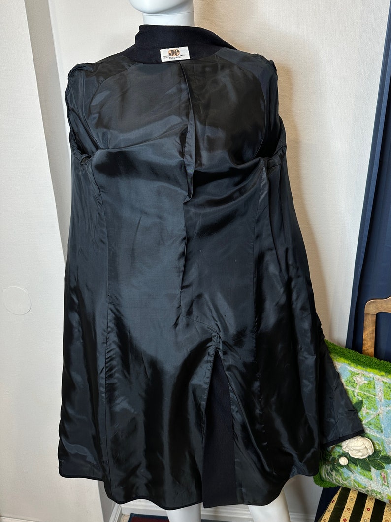 May include: Black long coat with a center back vent and a black satin lining. The coat has a JC Penney label.