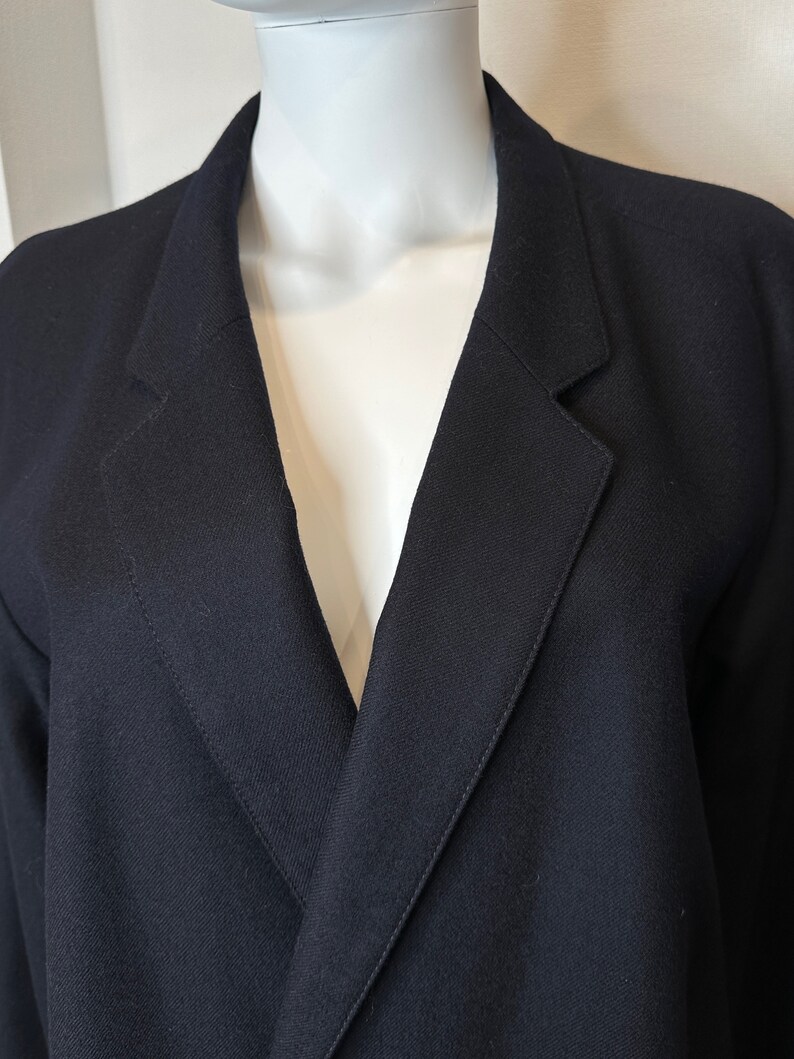May include: A black blazer with a deep V-neck and a single button closure.
