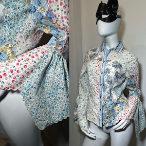 May include: A patchwork button-down shirt with long sleeves and a floral pattern in shades of blue, pink, and white. The sleeves have a flared, ruffled design. The shirt is displayed on a mannequin.