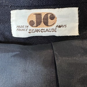 May include: A white label with brown text that reads "Made in France Jean Claude Paris". The label has a brown circle with the letters "JC" inside.