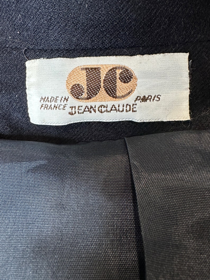 May include: A white label with brown text that reads "Made in France Jean Claude Paris". The label has a brown circle with the letters "JC" inside.