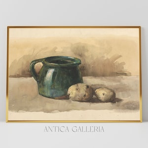 Puede incluir: Una pintura al agua de un bodegón con una jarra de cerámica verde y dos patatas sobre una superficie marrón claro. La pintura está enmarcada en un marco dorado y firmada "Antica Galleria".